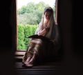 A woman sitting at the door and reading a book