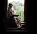 A woman sitting at the door and reading a book