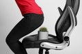 Woman sitting down into armchair with cactus on background, closeup. Hemorrhoids concept