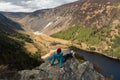 Woman sitting on the edge of a cliff, enjoying the landscape. Glendalough, Wicklow, Ireland.
