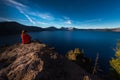 Woman Sitting on the Edge of a Cliff looking at Crater Lake Oreg