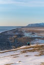 A woman sitting on the edge of mountain top, looking at the landscapes of Black Beach Reynisfjara Beach in Iceland