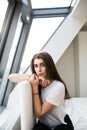 Woman sitting on the end of bed near big window Royalty Free Stock Photo