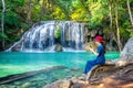 Woman sitting at Erawan waterfall in Thailand. Beautiful waterfall with emerald pool in nature. Royalty Free Stock Photo