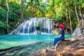 Woman sitting at Erawan waterfall in Thailand. Beautiful waterfall with emerald pool in nature.