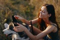 Woman sitting in a field with a dachshund dog smiling while spending time in nature with a friend dog in autumn at