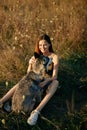 Woman sitting in a field with a dachshund dog smiling while spending time in nature with a friend dog in autumn at