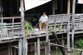 Woman sitting and fishing at retro wooden terrace in Rahang Canal Old Market