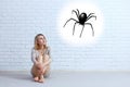 Young woman sitting on the floor and looking on imaginary spider. Royalty Free Stock Photo