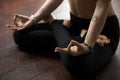 Woman sitting on floor in Lotus pose, making mudra gesture