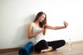 Woman sitting on floor and making selfie on smartphone in fitness gym Royalty Free Stock Photo