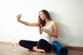 Woman sitting on floor and making selfie on smartphone in fitness gym Royalty Free Stock Photo