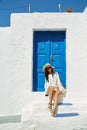 Woman sitting in front of a blue vintage entrance door Royalty Free Stock Photo