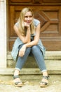 Woman sitting in front of wooden door on steps Royalty Free Stock Photo