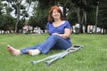 Woman sitting on the grass with a bandaged foot and crutches at her side Royalty Free Stock Photo