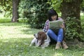 Woman sitting in the grass with her dog, reading the newspaper a Royalty Free Stock Photo