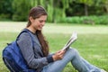 Woman sitting on the grass while reading a book Royalty Free Stock Photo