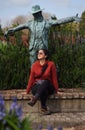 Woman sitting on Hamilton Gardens next to a scarecrow statue. Hamilton, Waikato, New Zealand. September 2020