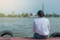 Woman sitting on the harbor alone and looking on the river