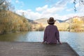 Woman sitting with her back on a wooden bridge looks to the future with a beautiful view of a mountain lake and forest Royalty Free Stock Photo