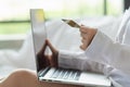 woman sitting in her room is happily shopping for gifts online with her credit card as she prepares for Christmas. woman uses