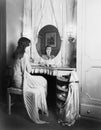 Woman sitting at her vanity table smiling into the mirror Royalty Free Stock Photo