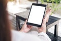 Woman sitting and holding black tablet pc with blank white desktop screen , feeling relaxed with sand and beach background Royalty Free Stock Photo