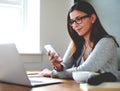 Woman sitting in home office checking mobile phone. Royalty Free Stock Photo