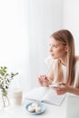 Woman sitting indoors near sweeties holding mobile phone.