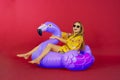 Woman sitting on inflatable flamingo in studio