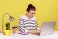 Woman sitting infront of laptop and typing on keyboard, looking at display with frowning face. Royalty Free Stock Photo