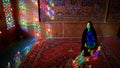 Woman sitting inside with stained glass window reflections of Nasir al-Mulk Mosque, Shiraz, Iran