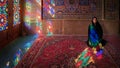 Woman sitting inside with stained glass window reflections of Nasir al-Mulk Mosque, Shiraz, Iran Royalty Free Stock Photo