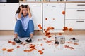 Woman Sitting On Kitchen Floor With Spilled Food