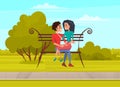 Woman sitting on lap of man on bench. Couple of lovers smiling and relaxing on date in nature