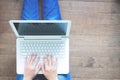 Woman sitting with laptop on wooden floor, hands typing message, Top view lifestyle concept