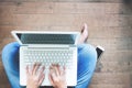 Woman sitting with laptop on wooden floor, hands typing message, Top view lifestyle