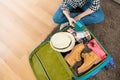 Woman sitting on living room floor packing luggage
