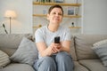 Woman sitting in living room holding remote control smiling. Royalty Free Stock Photo