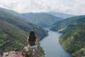 Woman sitting looking at landscape. Reservoir and mountains. Royalty Free Stock Photo