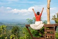 Woman sitting on lookout raising her arms up into the air in a moment of happiness and success Royalty Free Stock Photo