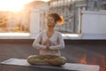 Woman sitting in lotus pose on mat and practicing yoga, female meditating indoors Royalty Free Stock Photo