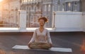 Woman sitting in lotus pose on mat and practicing yoga, female meditating indoors Royalty Free Stock Photo