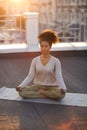 Woman sitting in lotus pose on mat and practicing yoga, female meditating outdoors Royalty Free Stock Photo