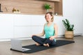 Woman sitting in a lotus position in front of the laptop