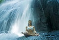 Woman sitting lotus yoga pose in spiritual relaxation serenity and meditation at stunning beautiful waterfall and rain forest in B Royalty Free Stock Photo