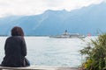 Woman sitting at Montreux promenade and enjoying views of Lake Geneva Lac Leman and traditional paddle steamboat cruising along