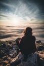 Woman sitting on mountain peak watching sunrise over a sea of fog