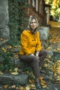 A woman is sitting near ancient buildings in autumn. Royalty Free Stock Photo