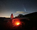 Woman is sitting near bonfire in mountains at night. Royalty Free Stock Photo